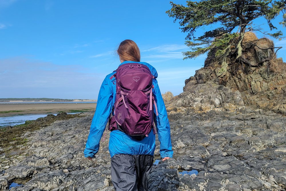 A hiker wearing the Zpacks Vertice Jacket with a backpack on on a coastal hike